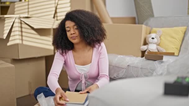 Afrykańska Amerykanka Pakuje Kartonowe Pudełko Przytulając Zdjęcie Nowym Domu — Wideo stockowe