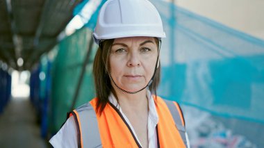 Orta yaşlı İspanyol kadın inşaatçı inşaat alanında duruyor.