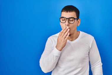 Gündelik beyaz gömlek giyen ve gözlük takan genç Arap adam ağzıyla ağzını kapatmaktan sıkılmış. Huzursuz ve uykulu.. 