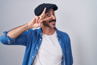 Sakallı İspanyol bir adam tecrit edilmiş arka planda duruyor. Yüzünde parmaklarıyla barış sembolü yapıyor. Gülümsüyor, zaferini gösteriyor. 