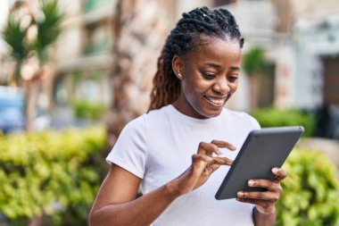 African american woman smiling confident using touchpad at street