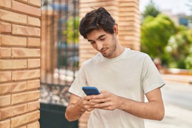 Sokakta akıllı telefon kullanan, kendine güvenen genç bir İspanyol.