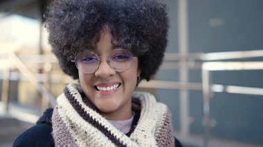 Sokakta kendinden emin gülümseyen Afrikalı Amerikalı genç bir kadın.