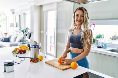 Mutfakta turuncu keserken kendine güvenen genç bir kadın.