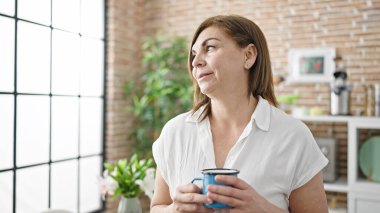 Orta yaşlı İspanyol kadın yemek odasında kahve içiyor.