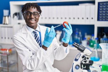 Afrikalı Amerikalı bilim adamı laboratuvarda domatese sıvı enjekte ediyor.