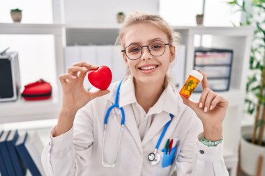 Kafkasyalı genç bir kadın elinde haplar ve yüzlerinde güzel bir gülümsemeyle gülümsüyor. diş gösterme. 