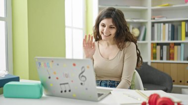 Genç ve güzel İspanyol kız öğrenci kütüphanede bilgisayar kullanıyor.