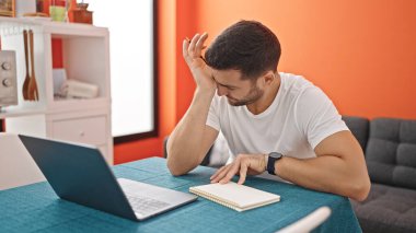 Yemek odasında dizüstü bilgisayar kullanan genç bir İspanyol.