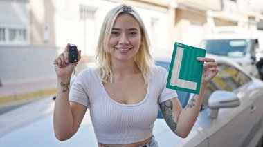Yeni ehliyet ve anahtarlar taşıyan genç, güzel İspanyol kadın caddede bekliyor.