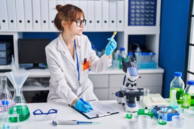 Laboratuvarda test tüpü tutan genç bilim kadını.