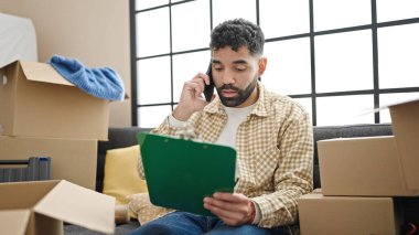 Genç İspanyol adam yeni evinde akıllı telefon okuyarak konuşuyor.