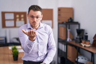 Ofisteki Latin asıllı genç adam kameraya bakıp havada bir öpücük savuruyor ve sevimli ve seksi oluyor. aşk ifadesi. 