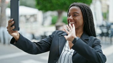 Afro-Amerikalı kadın iş adamı kahve dükkanının terasında video görüşmesi yapıyor.