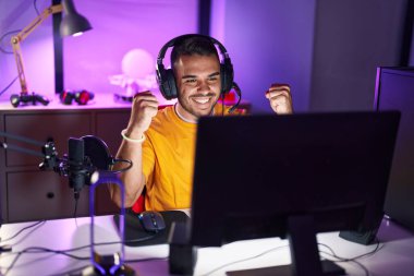 Oyun odasında İspanyol asıllı genç adam video oyunu oynuyor.