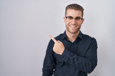 Kafkasyalı genç bir adam izole edilmiş arka planda mutlu bir şekilde duruyor. Yüzünde mutlu ve doğal bir ifadeyle, elleri ve parmaklarıyla yüzünü gösteren bir gülümseme var. 