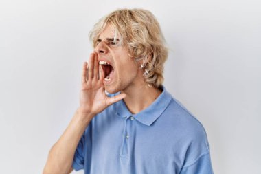 Genç modern adam izole edilmiş arka planda duruyor ve avazı çıktığı kadar bağırıyor. iletişim konsepti. 