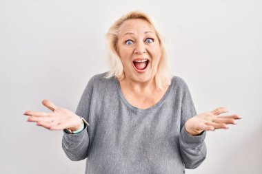 Beyaz arka planda duran orta yaşlı beyaz kadın çılgın ve başarıyı kollarını kaldırıp heyecanla haykırarak kutluyor. Kazanan konsept 