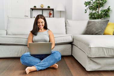 Evde dizüstü bilgisayar kullanan genç, güzel İspanyol kadın.