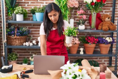 Çiçekçide dizüstü bilgisayar kullanan güzel İspanyol bir çiçekçi.