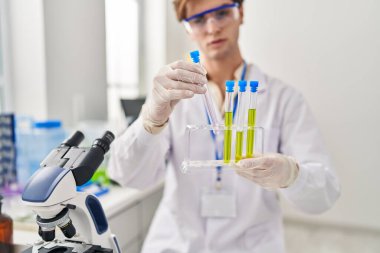 Kafkasyalı genç bilim adamı laboratuarda test tüpleri tutuyor.