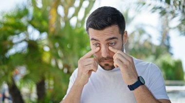 Ciddi bir ifadeyle ayakta duran, caddeye bakan genç bir İspanyol.