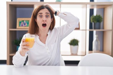 Esmer kadın bir bardak portakal suyu içiyor. Deli ve korkmuş. Elleri başının üstünde. 