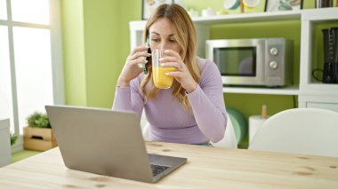 Genç ve güzel İspanyol kadın yemek odasında dizüstü bilgisayar kullanıyor.