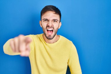 Mavi arka planda dikilen İspanyol adam kameraya kızgın ve sinirli olduğunu gösteriyor. 