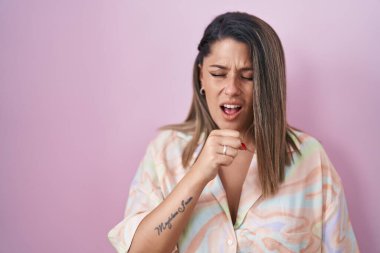 Blonde woman standing over pink background feeling unwell and coughing as symptom for cold or bronchitis. health care concept. 