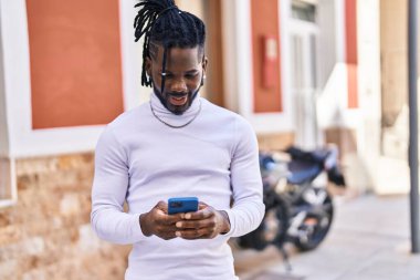 Afro-Amerikalı kadın sokakta akıllı telefon kullanarak kendine güveniyor.