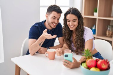 Young hispanic couple drinking coffee having video call at home