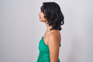 Young hispanic woman standing over isolated background looking to side, relax profile pose with natural face and confident smile. 