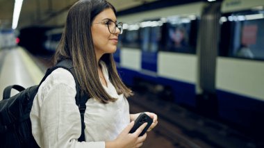 Madrid metro istasyonunda akıllı telefon kullanan güzel İspanyol bir kadın metroda bekliyor.