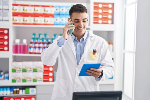 Fiatal Spanyol Férfi Gyógyszerész Beszél Okostelefonon Segítségével Touchpad Gyógyszertárban — Stock Fotó