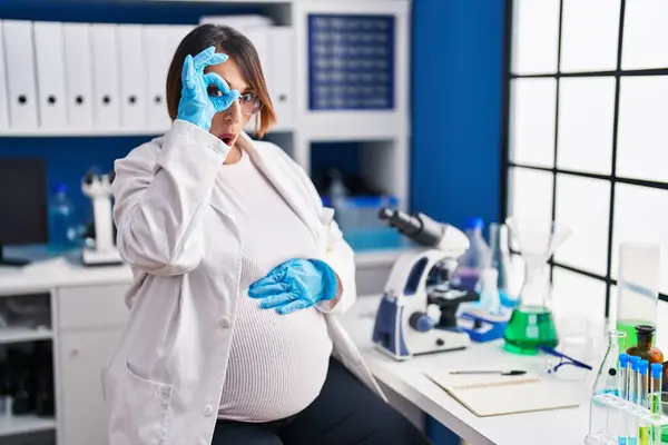 在科学家实验室工作的怀孕妇女做的姿势还好 脸上带着惊讶的表情 用手指看了看 不信的表情 — 图库照片
