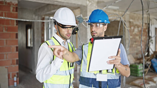 Два строителя читают документ на стройке