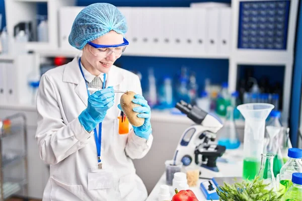 若いですブロンド女性科学者保持サンプルのジャガイモとともにピンセットで実験室 — ストック写真