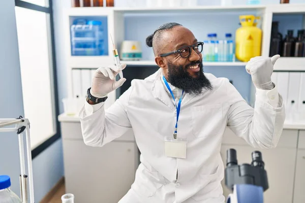 Afrykański Amerykanin Pracujący Laboratorium Trzymający Strzykawkę Skierowaną Kciukiem Górę Uśmiechnięty — Zdjęcie stockowe