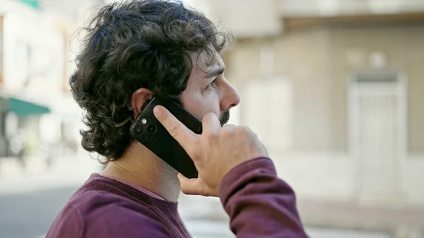 stock image Young hispanic man talking on smartphone with serious expression at street