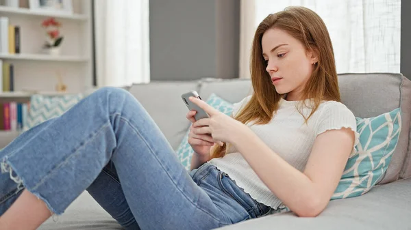 Jovem Loira Usando Smartphone Deitado Sofá Casa — Fotografia de Stock