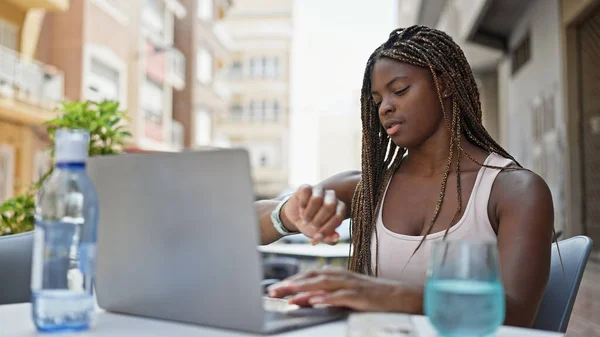 使用笔记本电脑观看咖啡店阳台的非洲裔美国妇女 — 图库照片