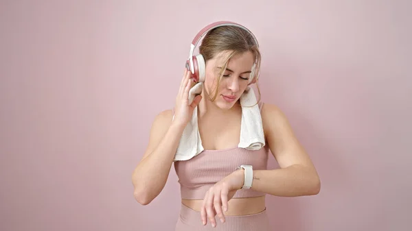 Mujer Rubia Joven Escuchando Música Mirando Cronómetro Sobre Fondo Rosa —  Fotos de Stock