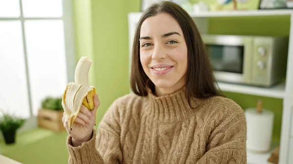 Νεαρή Όμορφη Ισπανόφωνη Γυναίκα Τρώει Μπανάνα Καθισμένη Στο Τραπέζι Της — Φωτογραφία Αρχείου