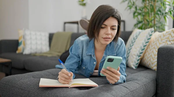 Genç Beyaz Kadın Evdeki Defterde Akıllı Telefon Yazıları Kullanıyor — Stok fotoğraf