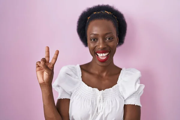 Afrykanka Kręconymi Włosami Stojąca Nad Różowym Tłem Uśmiechnięta Szczęśliwą Twarzą — Zdjęcie stockowe