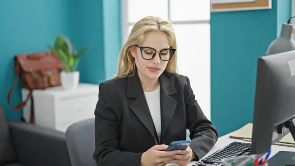 Young blonde woman business worker using smartphone working at the office