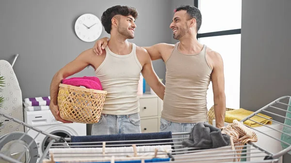 两个男人抱着柳条筐 在洗衣房里穿衣服 彼此拥抱 — 图库照片