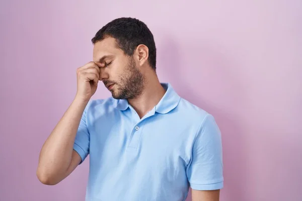 西班牙裔男子站在粉红的背景上 疲倦地揉揉鼻子和眼睛 感到疲倦和头痛 压力和挫败感概念 — 图库照片