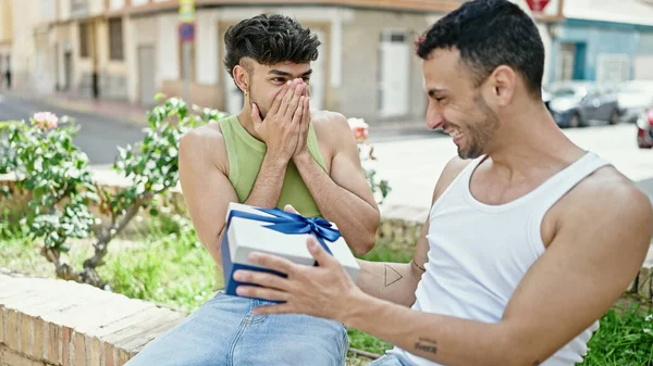 Stock image Two men couple surprise with birthday gift sitting on bench at park